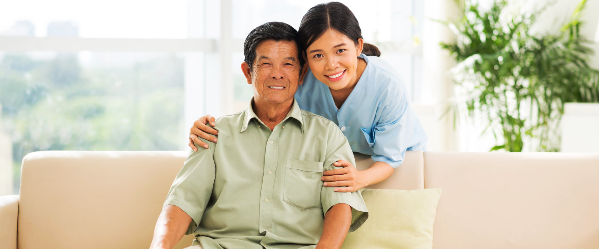 caregiver smiling with elderly man sitting on couch