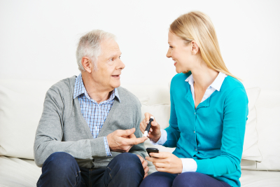 woman taking blood sugar level of elderly man