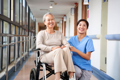 senior woman on wheelchair and caregiver smiling