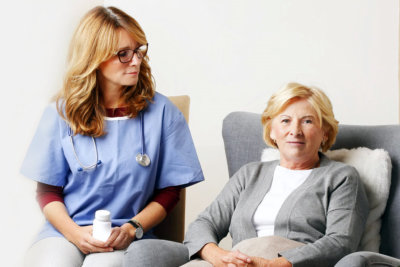 caregiver and senior woman sitting on sofa