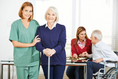 Caregiver working with happy senior people in nursing home