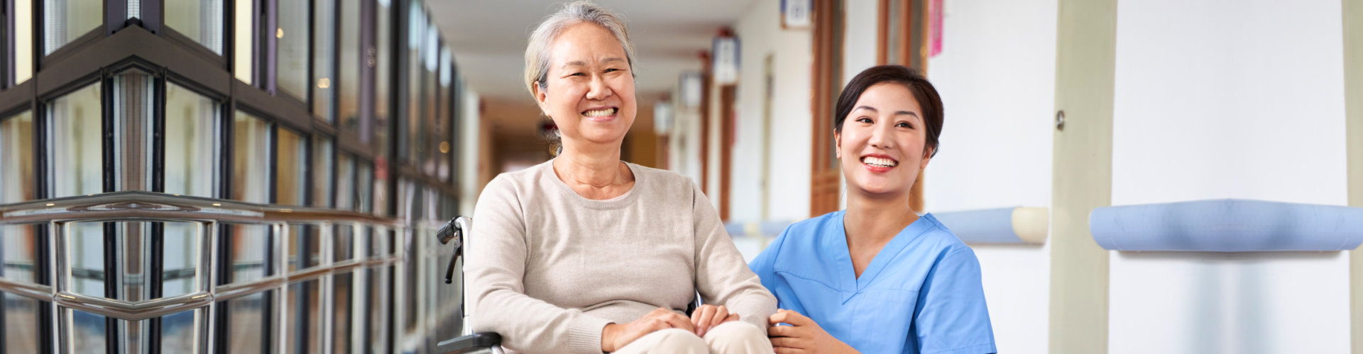 senior woman on wheelchair and caregiver smiling