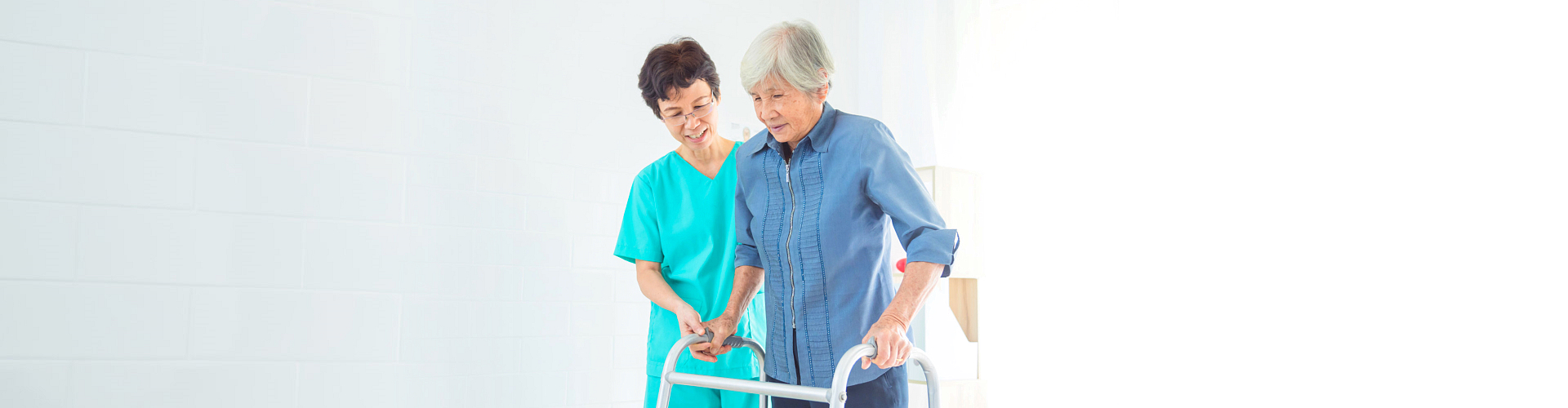 caregiver helping elderly woman to walk using a walker