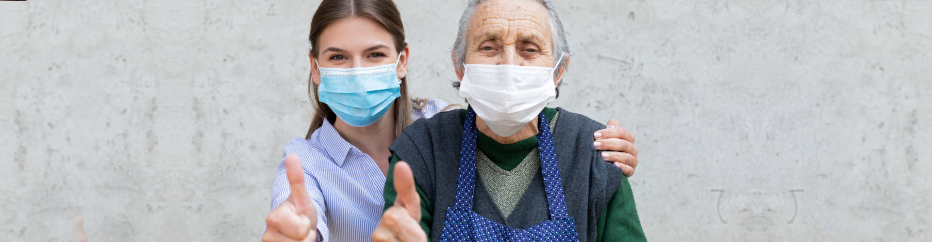 woman and elderly woman wearing mask signing thumbs up